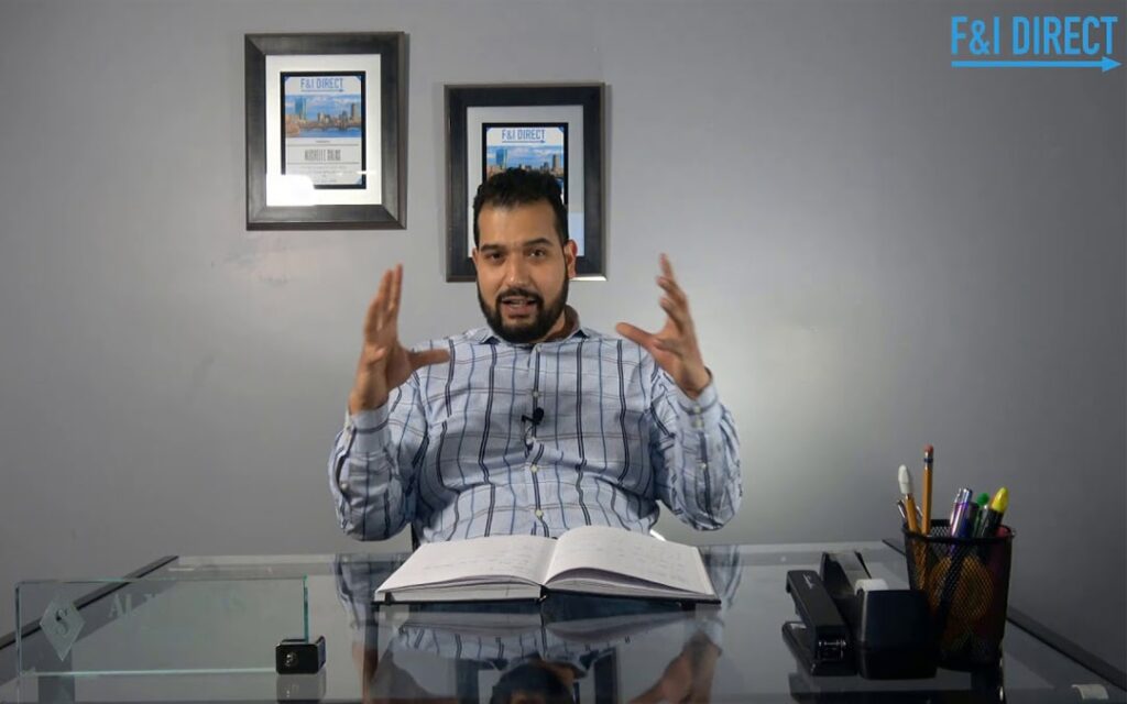 An image of a man named Al Salas explaining dealership to his customer, on his office table are open book, pens, pencils, black stapler, tape dispenser, and his glass name plate.